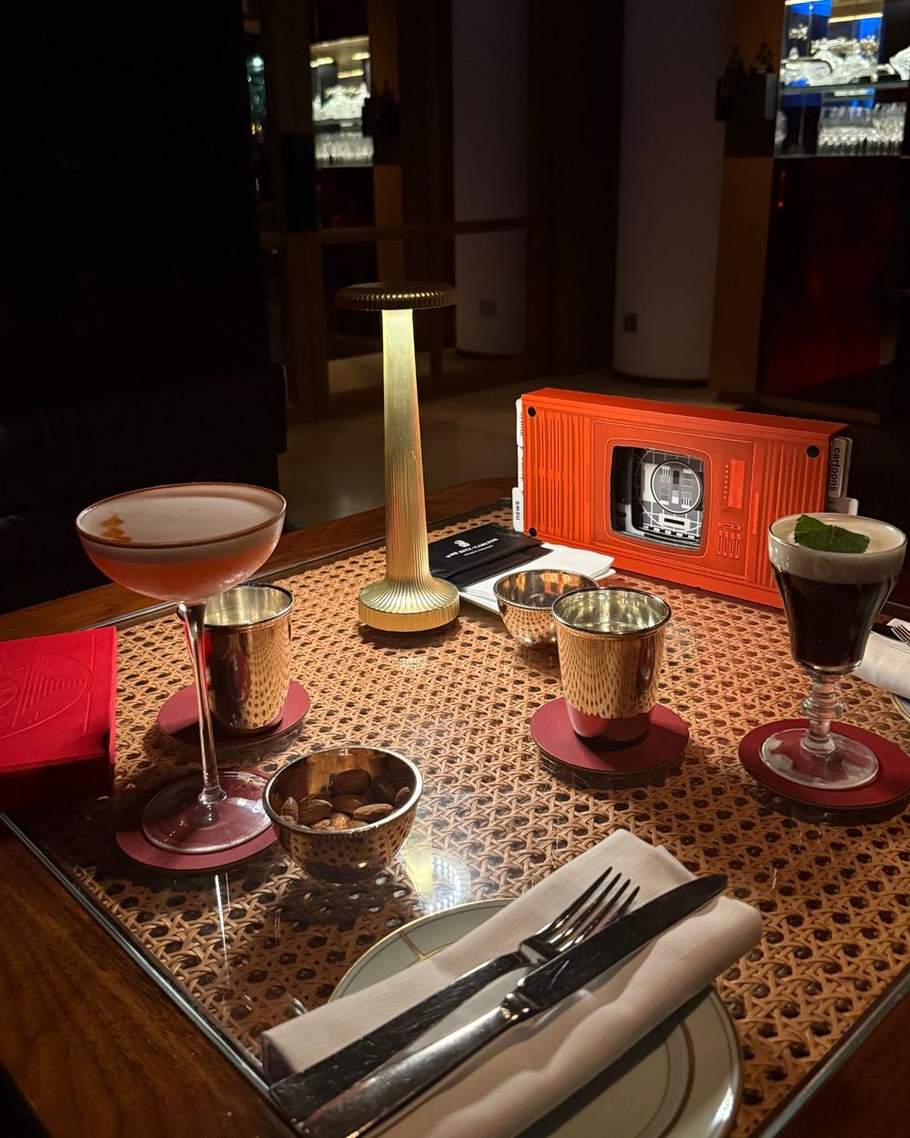 A late table for two at a hotel bar: a cocktail, an Irish coffee and a gold lamp